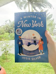 a person holding up a book about winter in new york