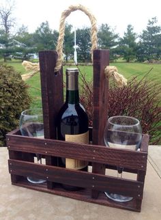 a wine bottle and two glasses in a wooden crate