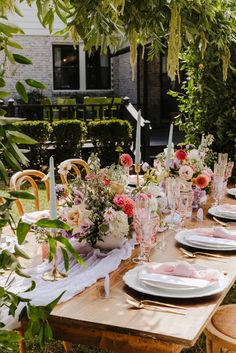 an outdoor table set with plates and place settings for a dinner party in the garden