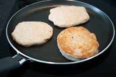 two hamburger patties cooking in a frying pan