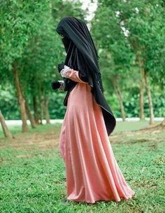 a woman in a hijab is walking through the grass