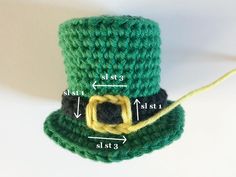 a crocheted green top hat with a yellow ring on the front and side