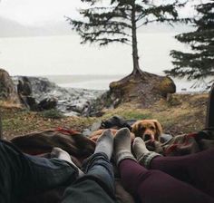 two people and a dog are laying on the ground with their feet up in the air