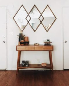 a wooden table topped with a mirror next to a wall mounted shelf filled with vases