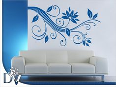 a white couch sitting in front of a wall with blue flowers on it's side