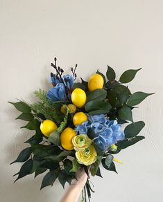 a hand holding a bouquet of flowers and lemons