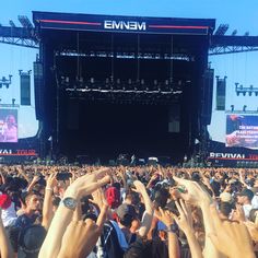 a large group of people standing in front of a stage with their hands in the air