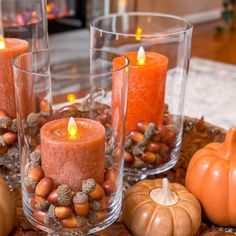 some candles are sitting on a table with pumpkins and acorns