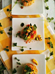 three white plates topped with food on top of a yellow and white checkered table cloth