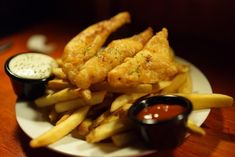 fish and fries on a plate with dipping sauce