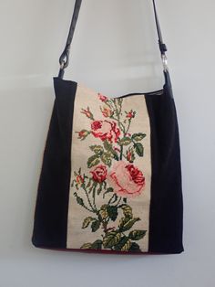 an embroidered purse with flowers on it hanging from a hook in a wall next to a white wall