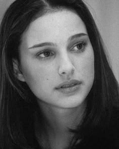 a black and white photo of a woman with long dark hair looking at the camera