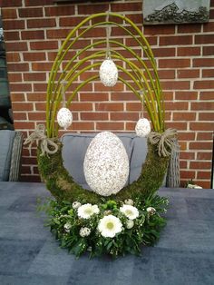 an arrangement of flowers and grass on a table in front of a brick wall,