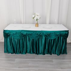 the table is covered with green cloth and white flowers