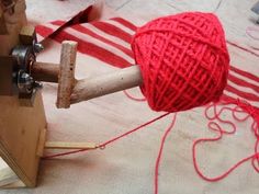 a red ball of yarn is hooked up to a wooden cleaver on a table