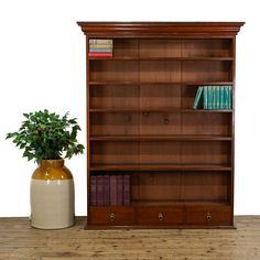 a wooden bookcase next to a potted plant