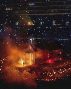 an aerial view of a church at night with bright lights on the ground and buildings in the background