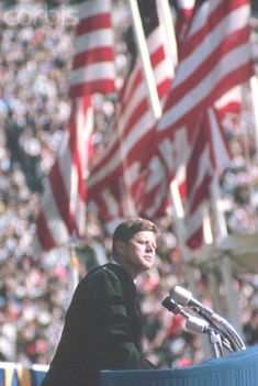 a man standing at a podium in front of american flags