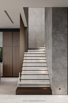 there is a staircase leading up to the second floor in this modern house with marble walls and floors