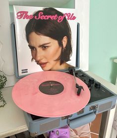 a record player with a pink disc in front of a magazine on top of it