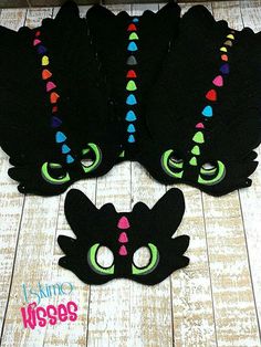 four black cat masks with green eyes on wooden floor