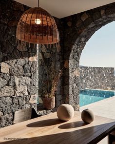 a table with two balls on it next to a stone wall and an outdoor swimming pool