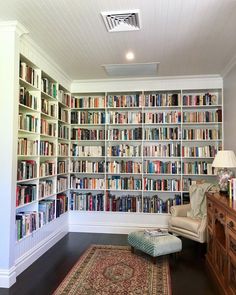 a living room filled with lots of books on top of a book shelf next to a chair