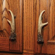 two deer antlers mounted to the side of a wooden cabinet door with beaded handles