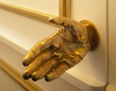 a gold hand is on the handle of a door