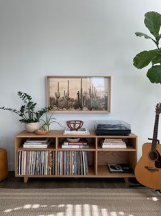 a living room with a guitar, record player and plant