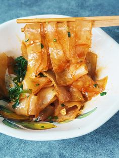 a white plate topped with food and chopsticks