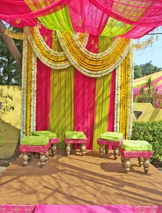 a decorated stage with green chairs and yellow drapes