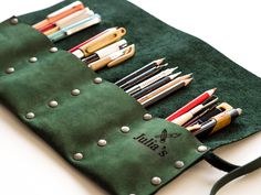 a green bag filled with pens and pencils