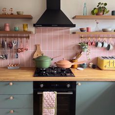 a stove top oven sitting inside of a kitchen next to a counter with pots and pans on it