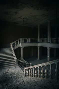 an abandoned building with stairs and railings in the middle of it's dark room