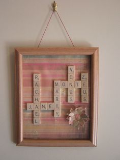 scrabble tiles are hung on the wall above a wooden frame with pink flowers