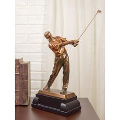 a bronze statue of a man holding a golf club on top of a wooden table