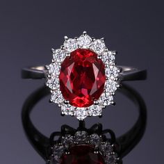 a close up of a ring with a red stone in the middle and white diamonds around it