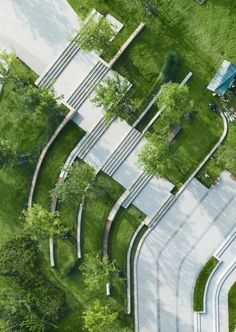 an aerial view of a park with trees and benches in the grass, looking down