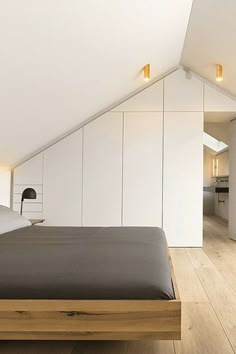 a bed sitting under a window in a bedroom next to a white chair and wooden floor