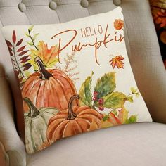 a pillow that says hello pumpkin sitting on a chair with fall leaves and acorns