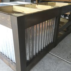 a wooden table with metal slats on the top and bottom, sitting in a garage