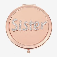 a pink compact mirror with the word sister written in crystal stones on it's side