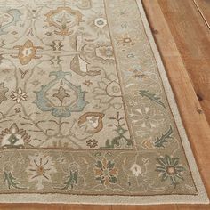 a beige rug with an ornate design on the top and bottom is sitting on a wooden floor