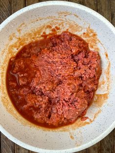 a white bowl filled with sauce on top of a wooden table