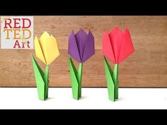 three origami tulips in front of a wooden wall with red ted art sign