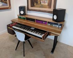 there is a keyboard and speakers on the table in front of the painting that hangs on the wall