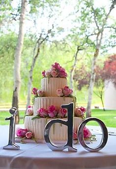 a wedding cake sitting on top of a table with the letter d spelled out in front of it