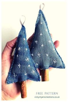 two small christmas trees made out of blue jeans with white stars are held in the palm of someone's hand