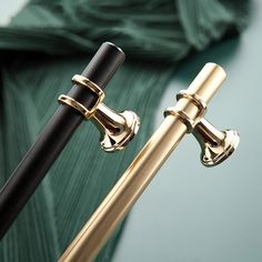 a gold and black umbrella stand next to a green leafy background, with the handle extended